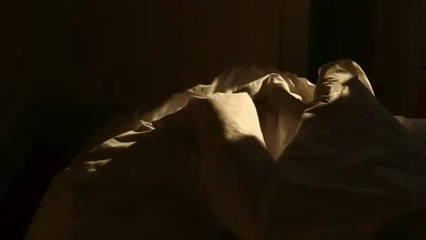 an unmade bed in a dark room