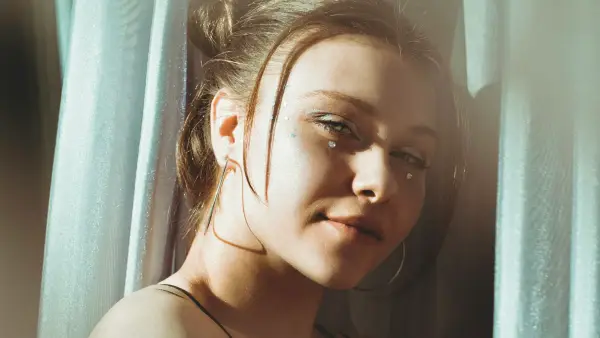 a woman with a hoop earring standing in front of a curtain
