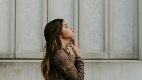 woman in brown long-sleeved top standing beside wall