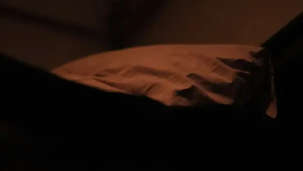 A person lying awake in soft lamplight, lost in thought