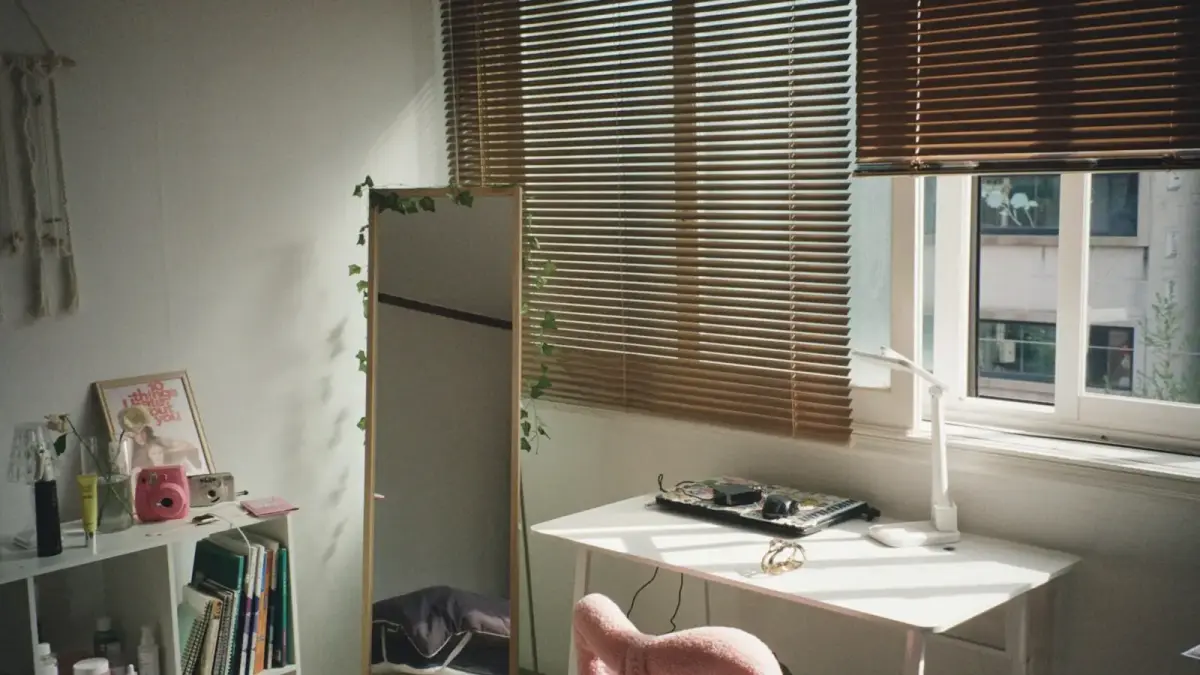 Bright room with a desk, pink chair, and window blinds