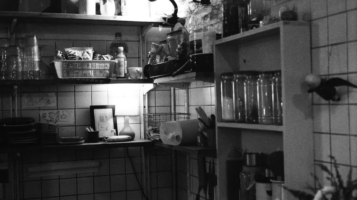 A cluttered kitchen shelf with jars and utensils