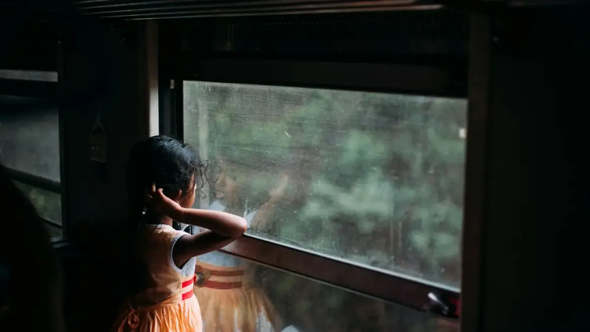 girl in orange sleeveless dress looking at the window