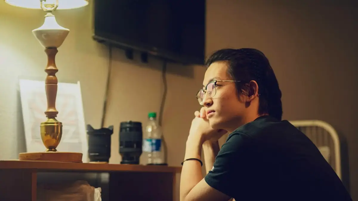 Person sitting alone at a desk in warm afternoon light, contemplative