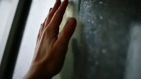Hand rests against a foggy window