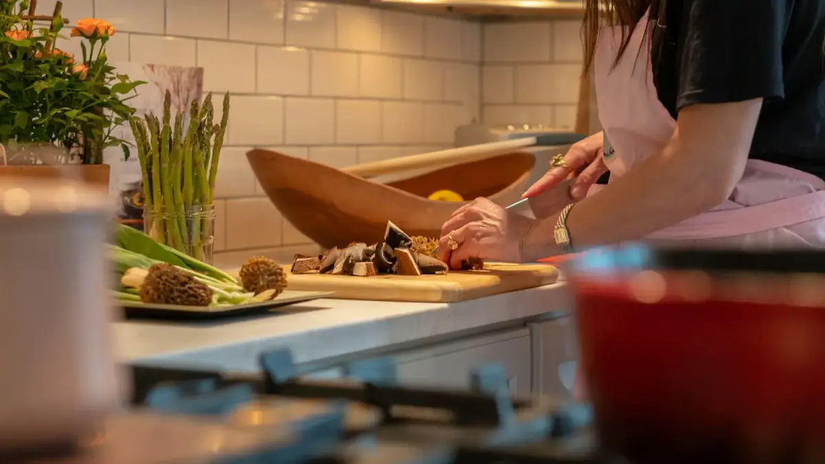 a woman in a kitchen chopping vegetables on a cutting board