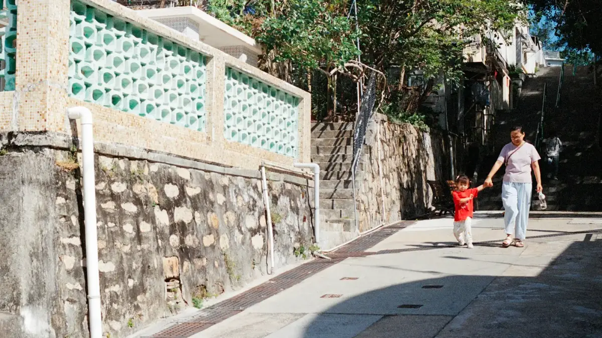 Woman and child walking down a sunny street.
