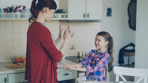 A mother and daughter are playing in the kitchen.