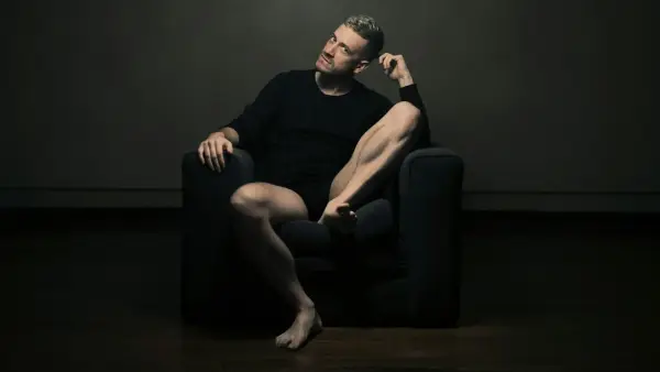 man in black tank top sitting on black sofa chair