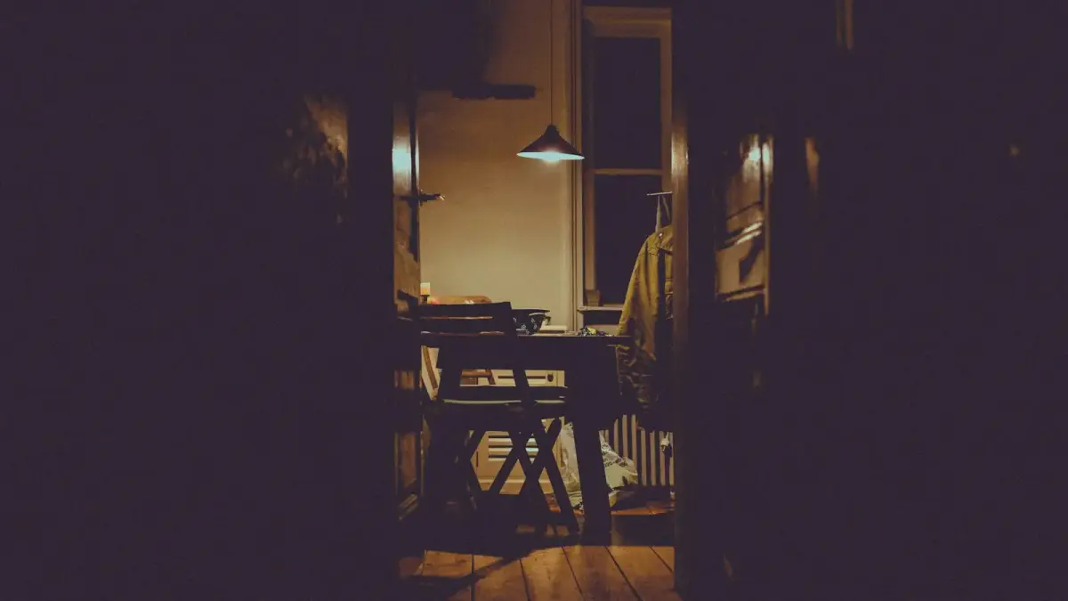 A man checking a door lock in the warm hallway light of his home before bed