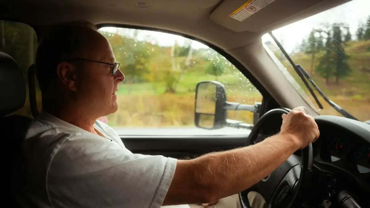 A man driving a car on a rural road