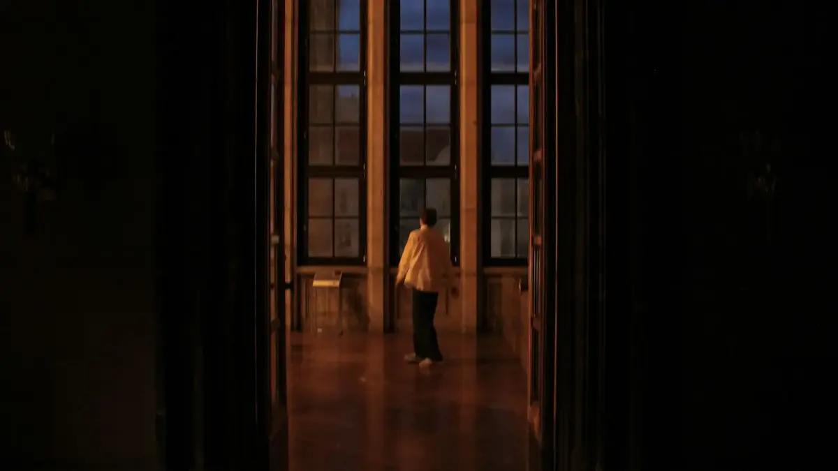 Person stands in grand room with large windows