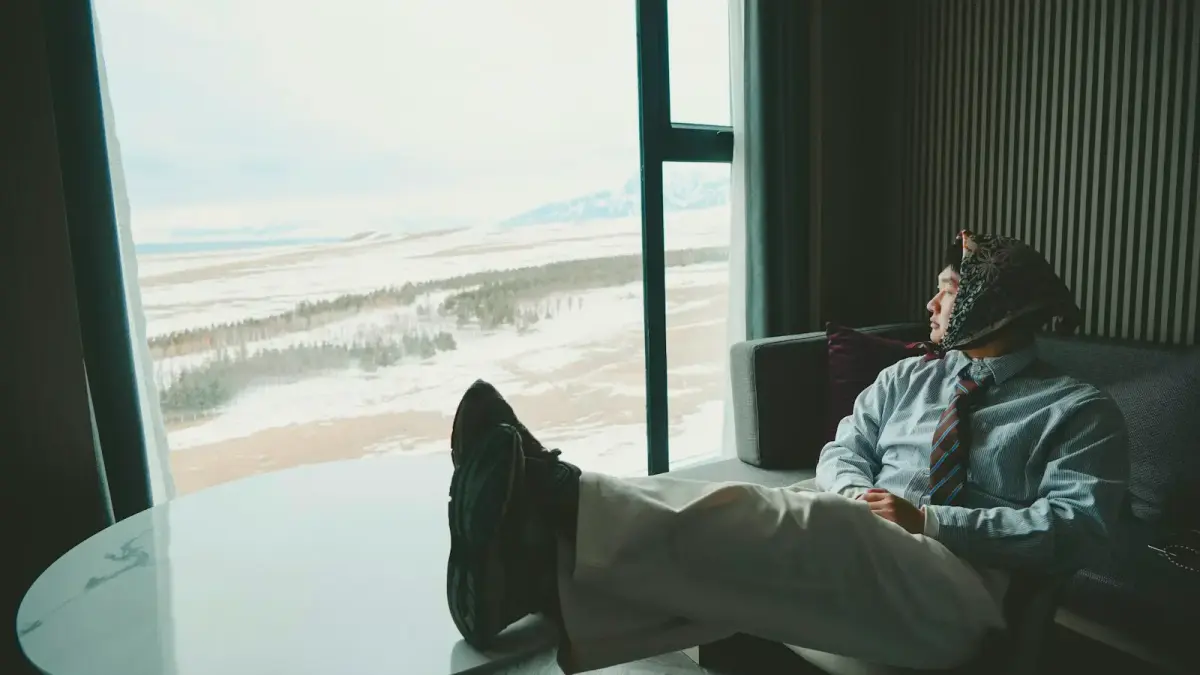 Man in suit looking out window at snowy landscape