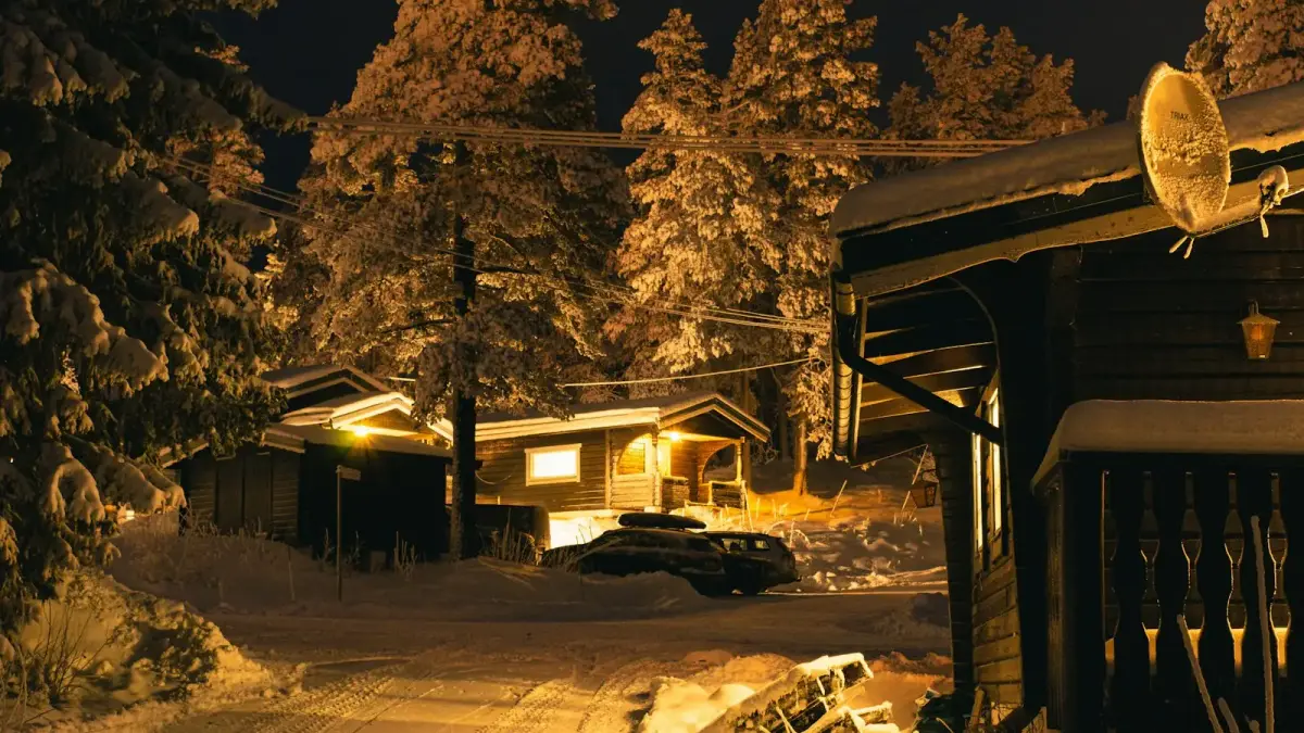 a snowy road with a house and a car in the background