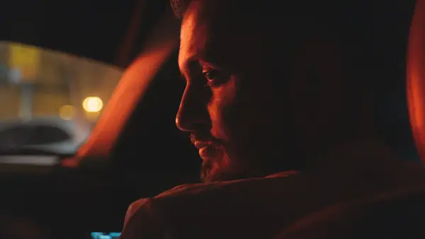 A person sitting alone on a couch late at night in warm lamp light