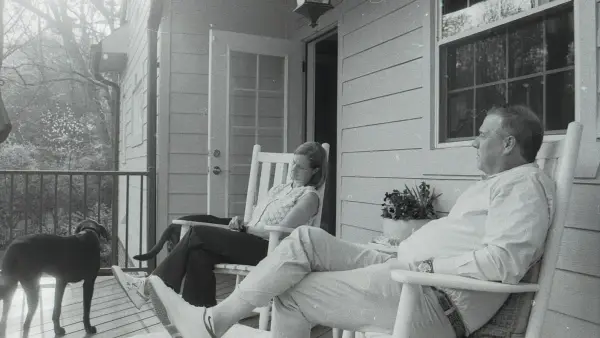 A couple and their dog relaxing on a porch.