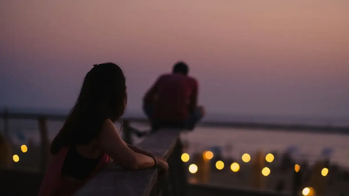 A couple in a kitchen in warm evening light, the quiet tension of a conversation that is about more than what it seems