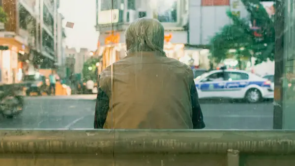 woman in brown coat standing near the road during daytime
