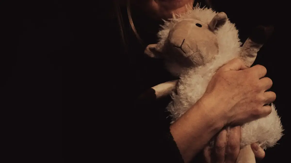 Woman hugging a stuffed sheep toy