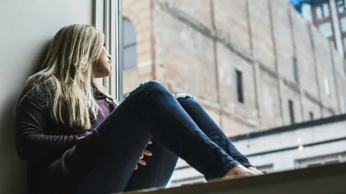 woman sitting on window watching sky
