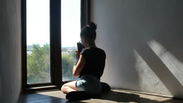 Woman sitting quietly at a kitchen table in morning light