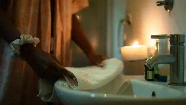 Woman folding a towel by a sink with candle