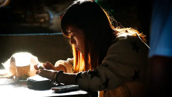 a woman sitting at a table using a cell phone