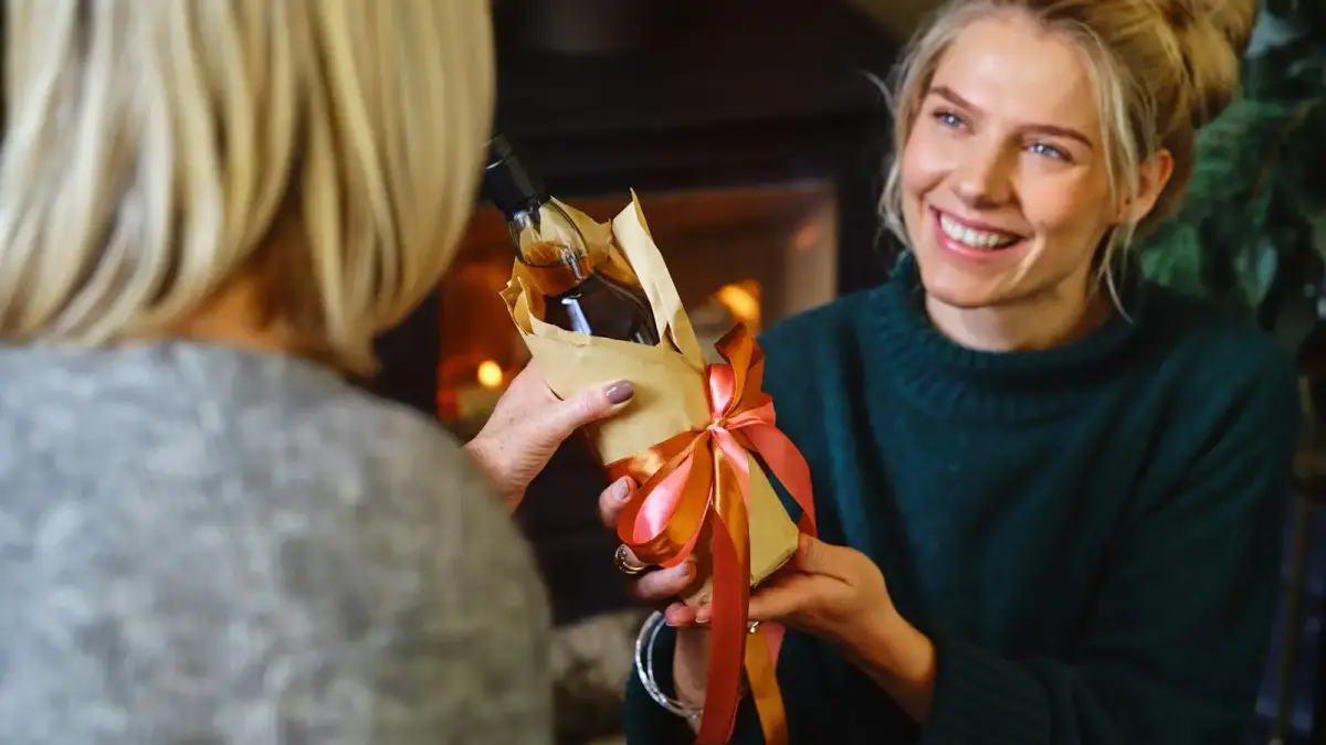 a woman holding a wrapped present in front of another woman