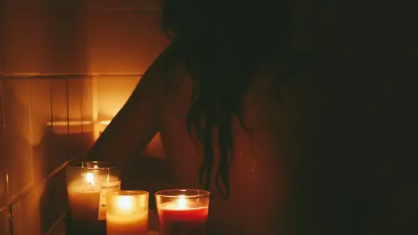 a woman sitting in front of candles in a bathroom