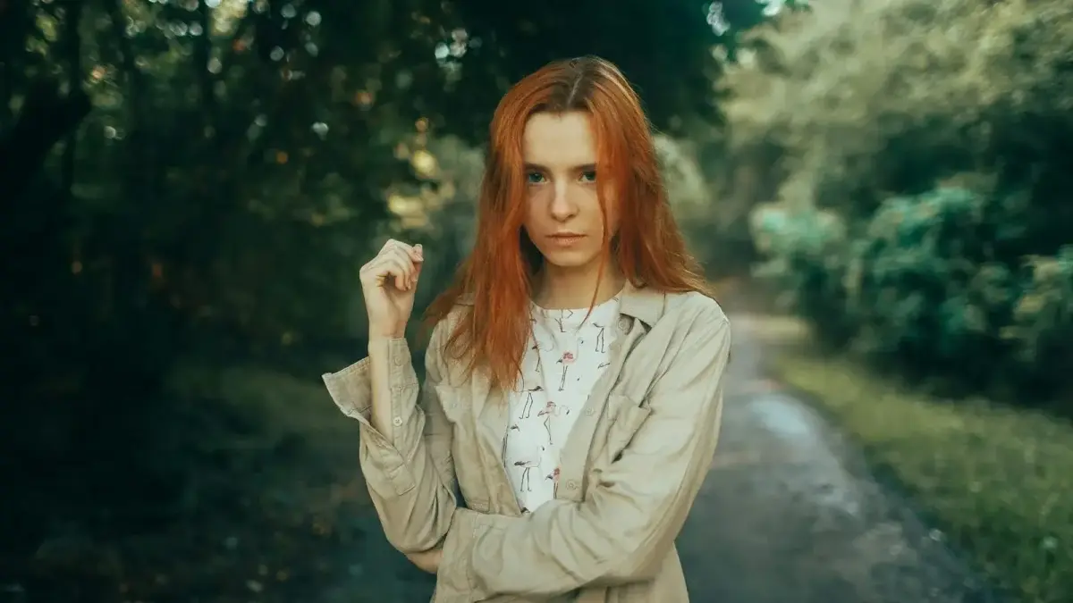 Young woman with red hair in a forest path