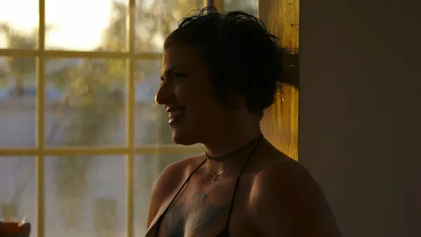A person laughing softly in warm light, a moment of vulnerability hidden behind humor