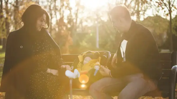 A couple tends to their baby on a bench.